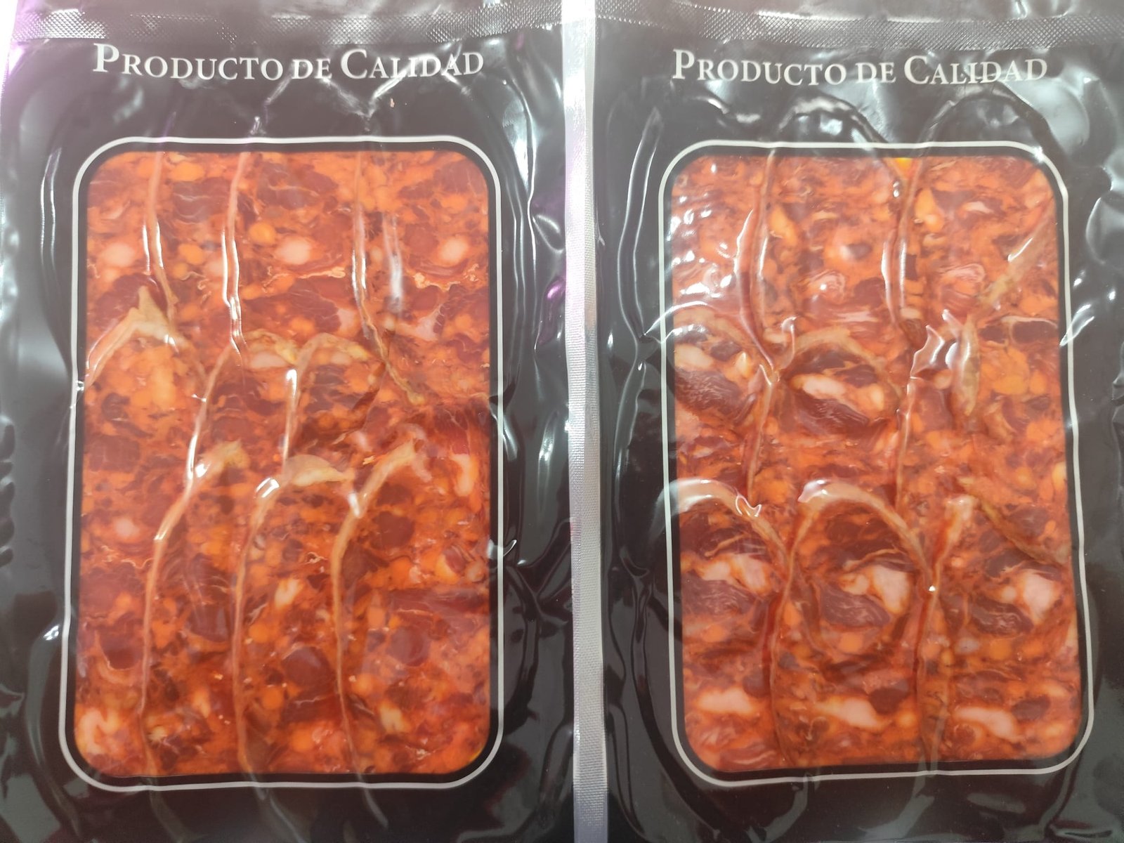 Dos envases al vacío de chorizo cular extremeño loncheado, con lonchas de pimentón rojo y magro visible